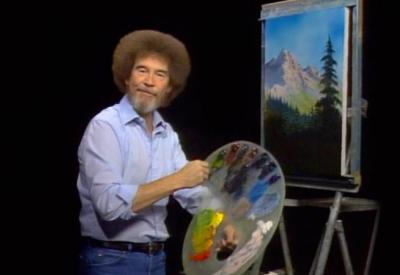 bob ross holds paint brush and palette in front of a painting